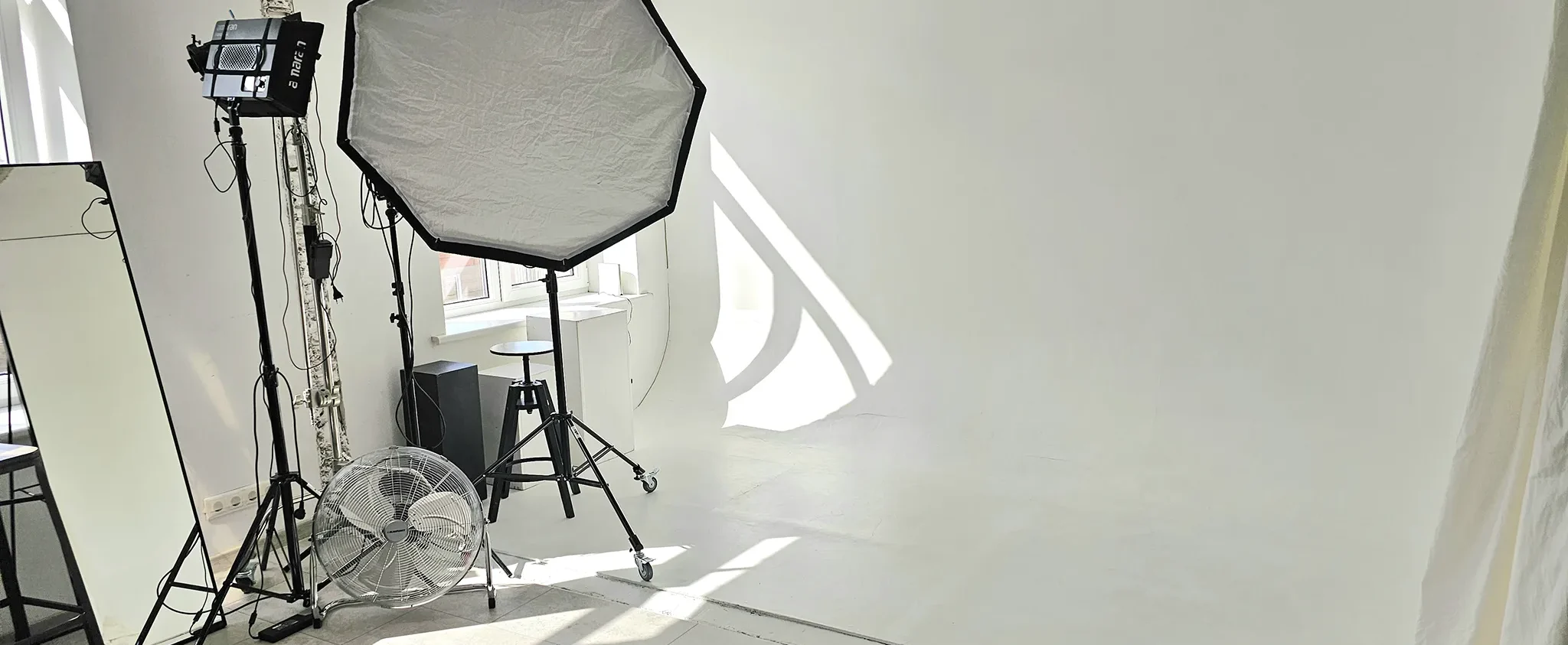 Photography studio setup with a large octagonal softbox, a studio light, and cables on a tiled floor.